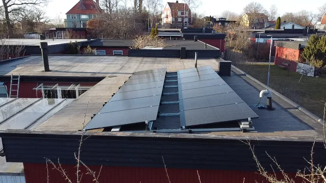Paneler monterade i ett sammanhängande fält på ett platt tak, sett från marken