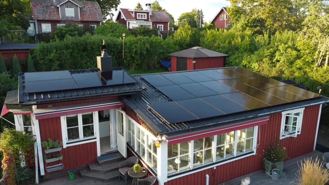 Huset med glasveranda och panelerna på det platta taket, sett från luften