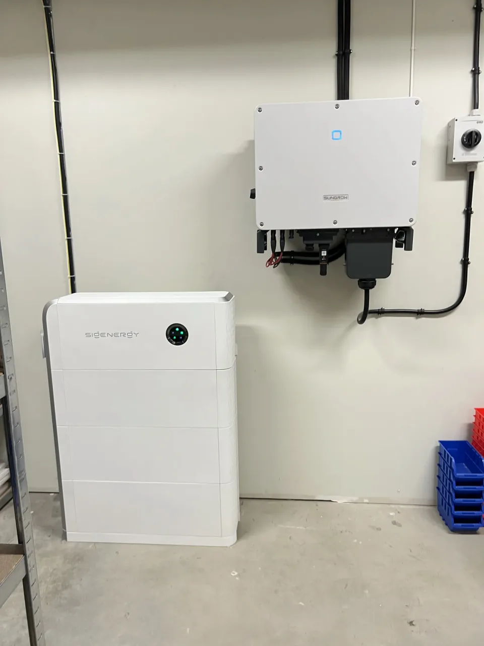 Sungrow hybridväxelriktare på vägg med Sigenergy batteri intill, kabelrör dragna till säkerhetsbrytare