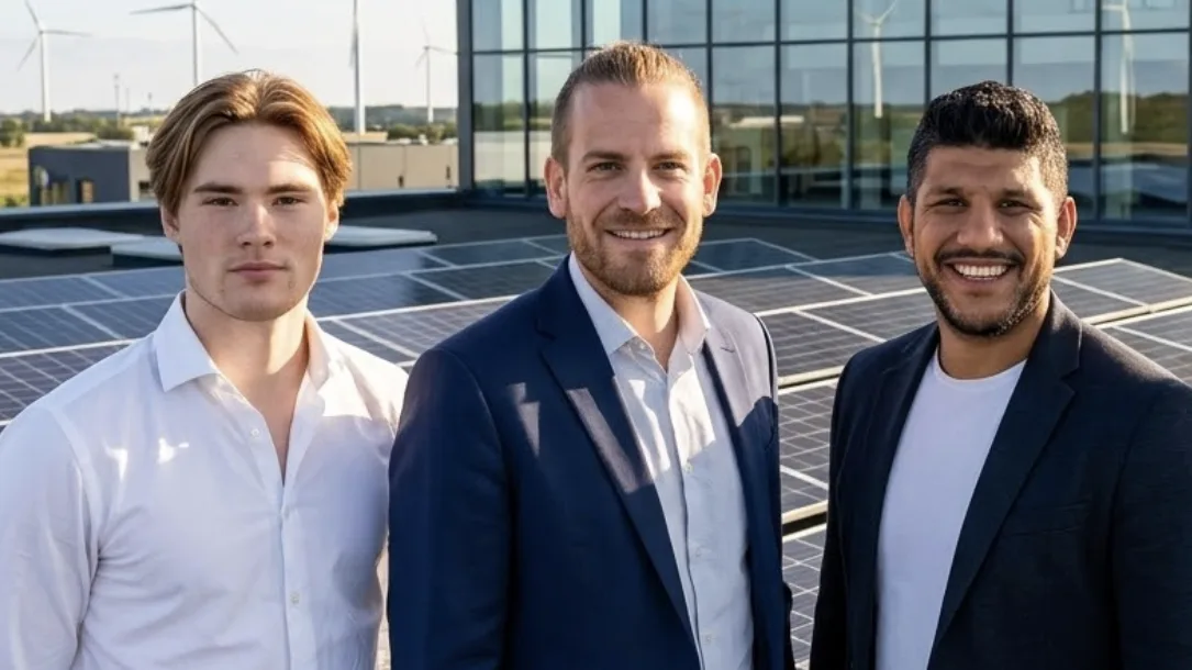 Tre ur teamet på ett tak med solceller, med vindkraftverk och en kontorsfasad bakom sig